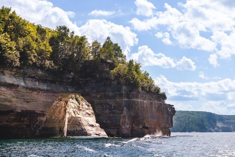 Panoramic view of the Pictured Rocks National Lakeshore with sandstone cliffs and turquoise waters under blue skies.