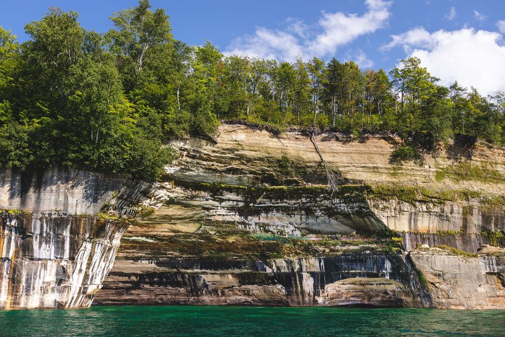 Dramatic rock formations and cliffs line the turquoise waters of Pictured Rocks National Lakeshore in Michigan.