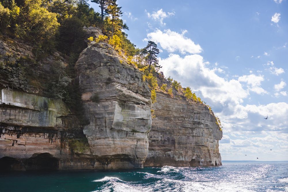 Scenic panoramic view of Pictured Rocks National Lakeshore with turquoise waters and layered sandstone cliffs.