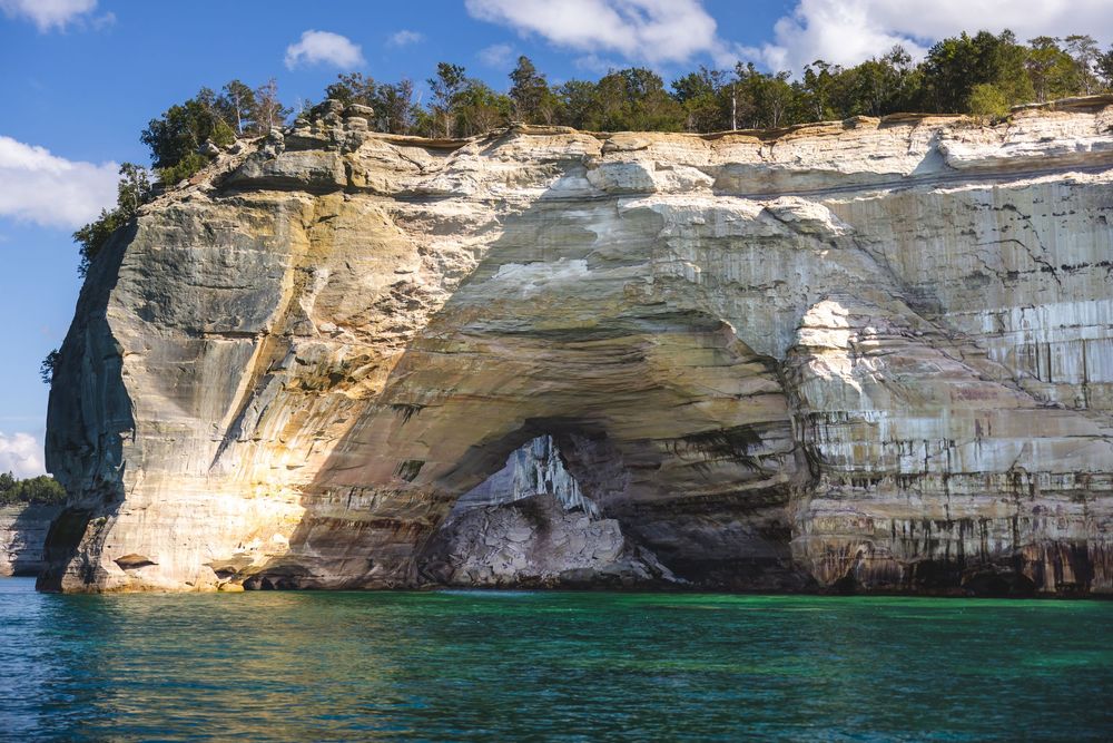 Pictured Rocks National Lakeshore features dramatic limestone cliffs and natural stone arches along Lake Superior's shoreline.