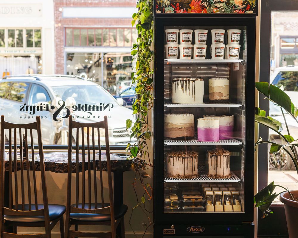 A cozy cafe interior with wooden chairs and tables arranged near large windows with natural light streaming in.