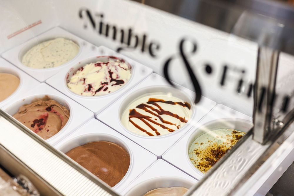 Ice cream display case showing various flavors with chocolate drizzle and toppings at Simple and Fresh ice cream shop.