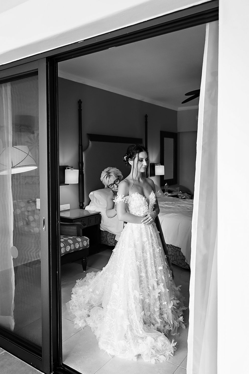 White wedding dress displayed in a modern room with large glass windows and neutral walls.