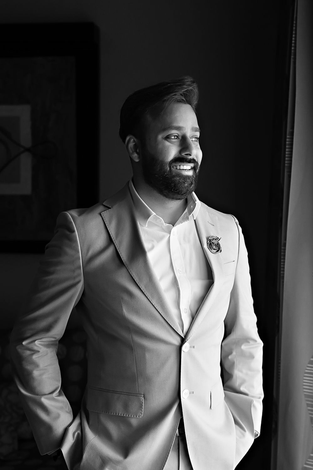 A black and white photo series showing a person in a white suit jacket standing in dramatic lighting.