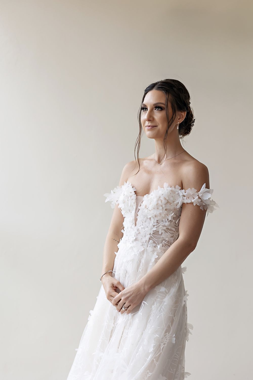 An elegant off-shoulder wedding dress with delicate floral appliques and sheer details captured in various poses.