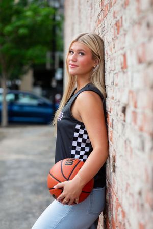 Casual fashion photoshoot against a brick wall featuring a basketball and checkered pattern tank top.