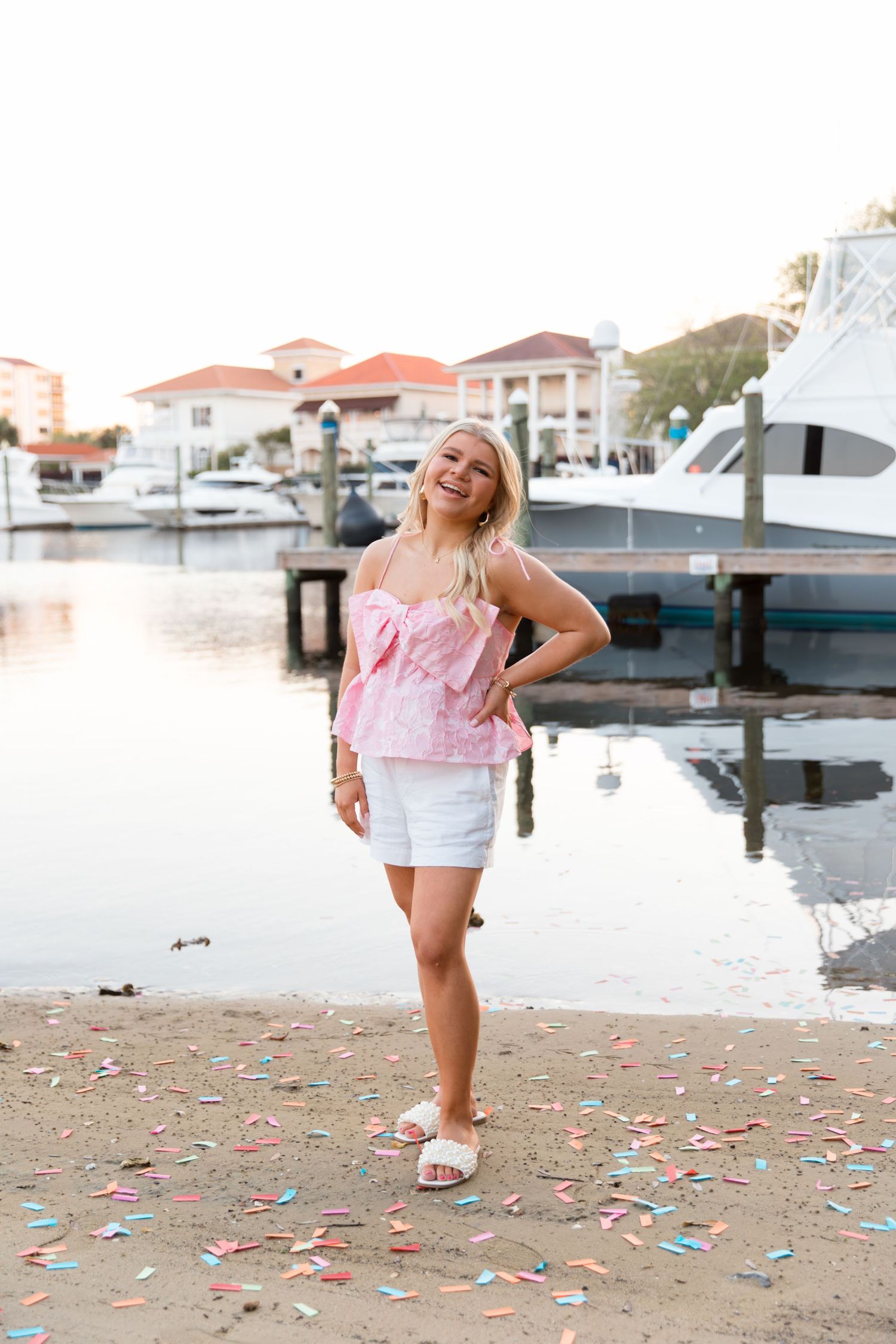 A playful scene by the marina with scattered confetti on the ground and boats docked in the background.