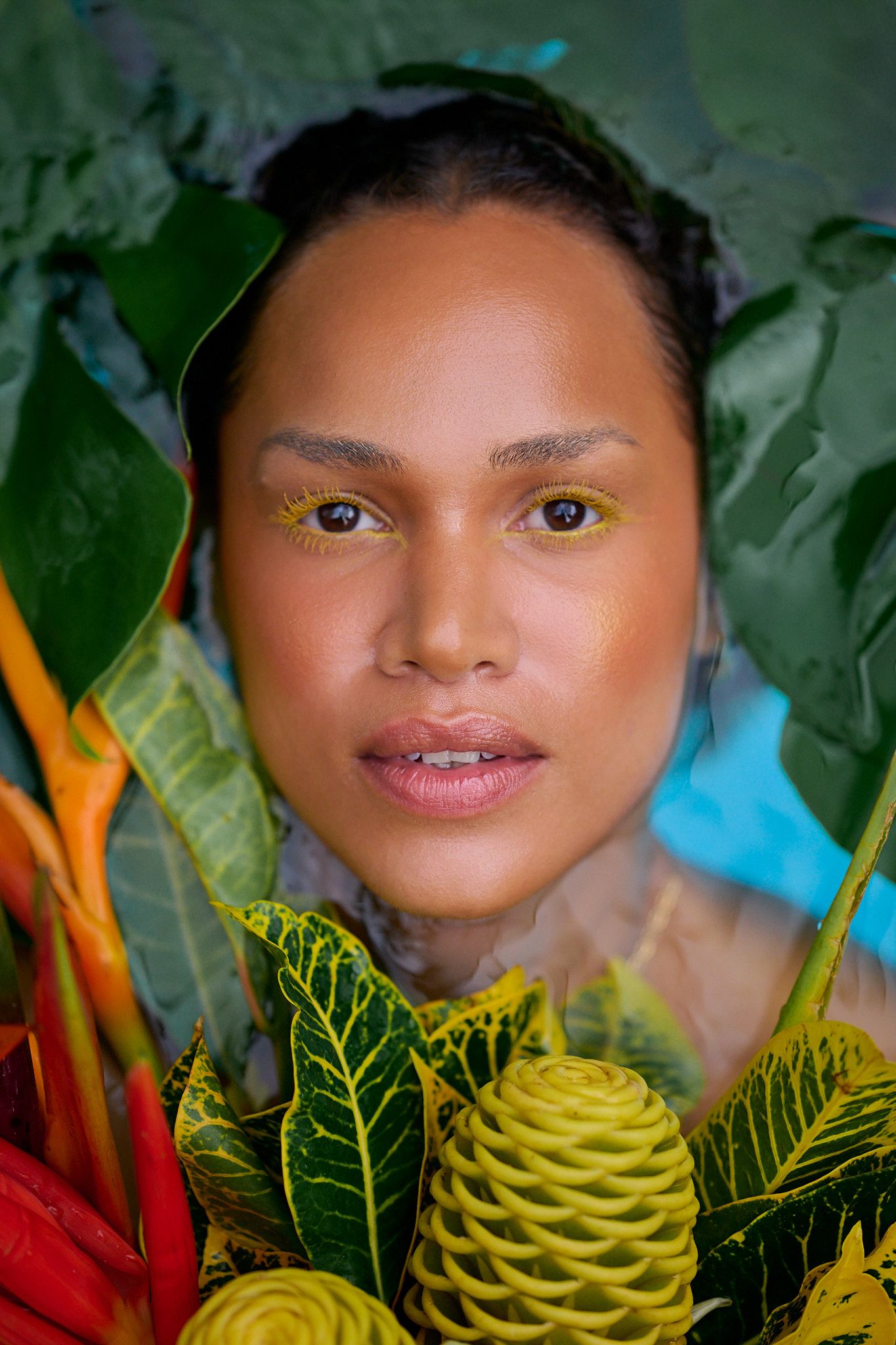 Portrait surrounded by vibrant tropical foliage with yellow heliconia flowers and green leaves in natural lighting.