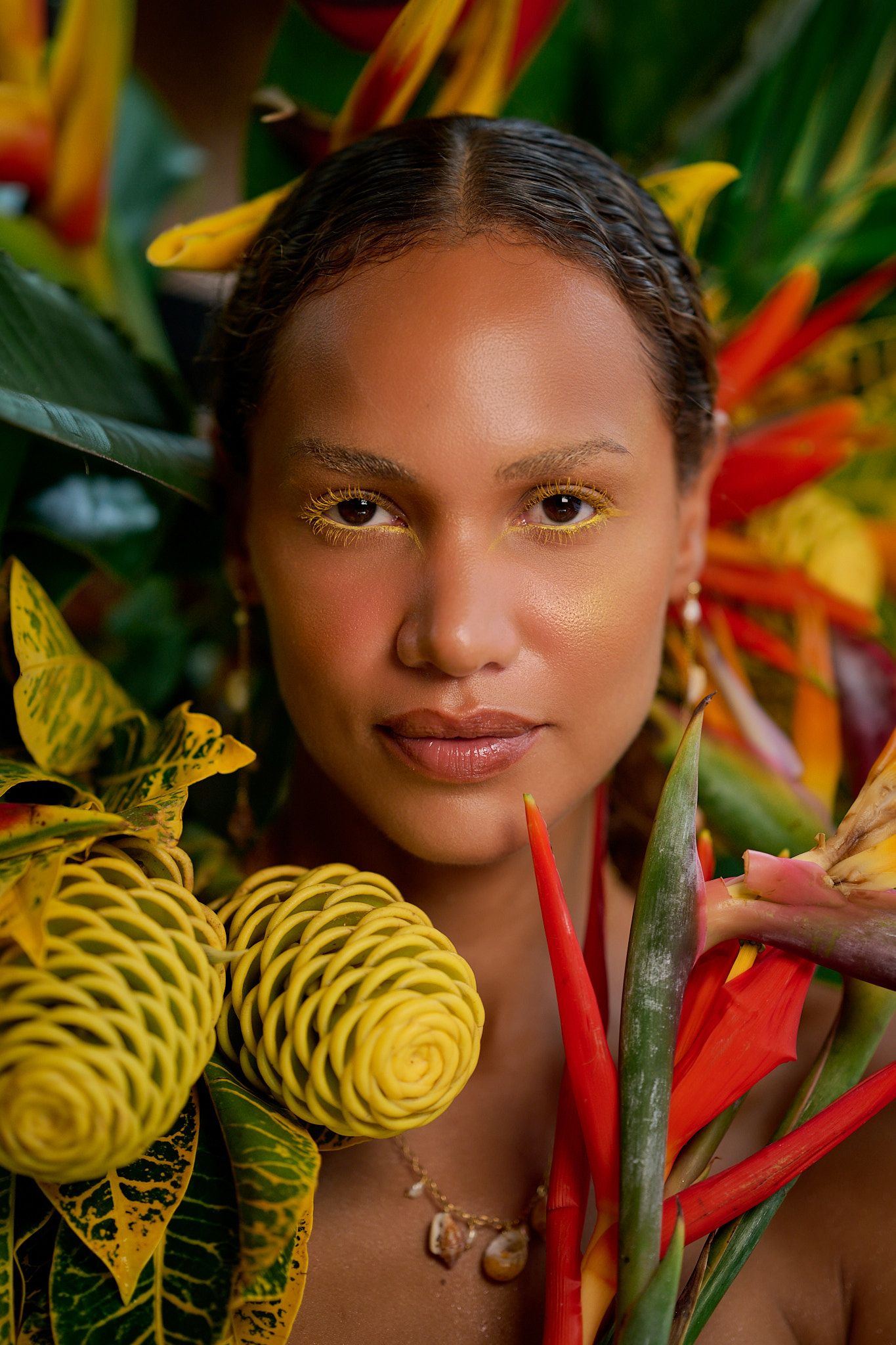 A series of close-up shots with tropical flowers including yellow heliconia and red bird of paradise blooms.