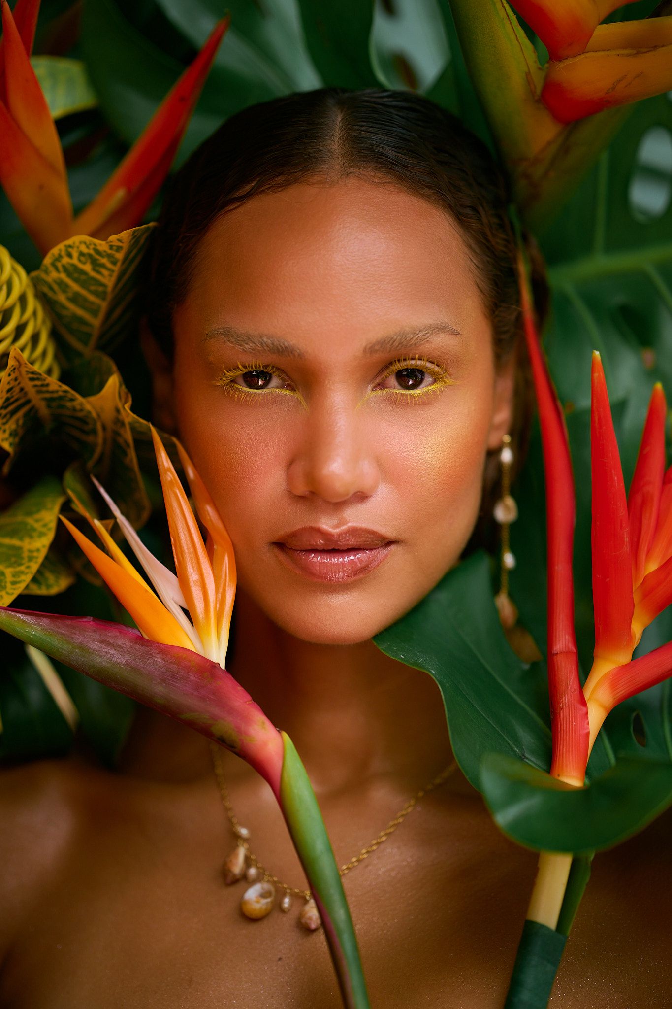 Artistic portrait surrounded by vibrant red and orange birds of paradise flowers and tropical green foliage.