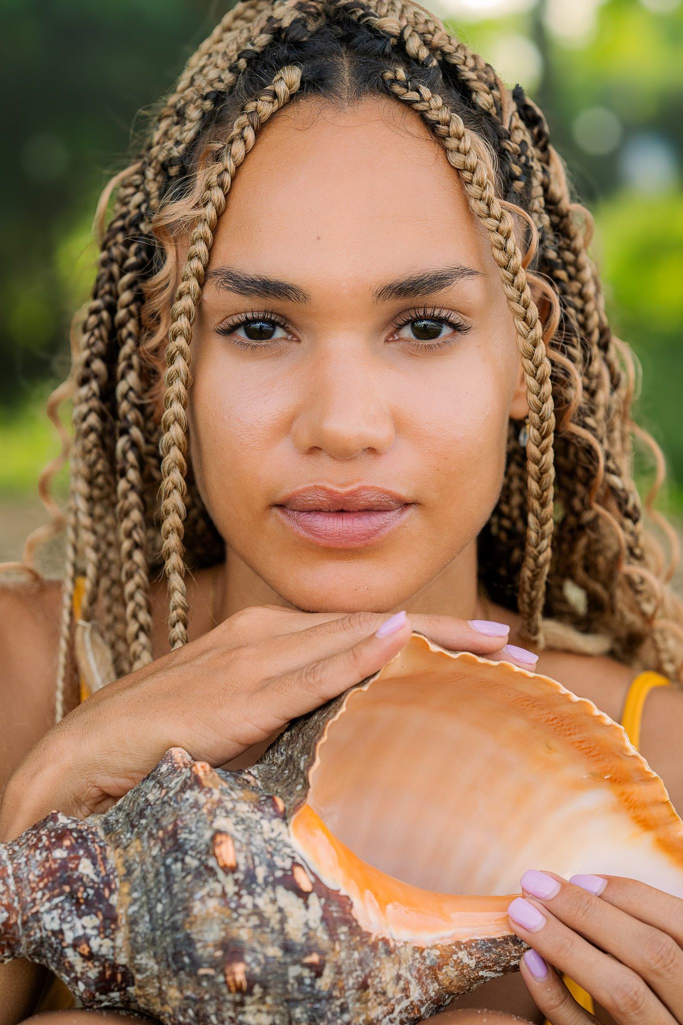 A series of artistic portrait shots showing a person with blonde box braids posing with a natural wood log outdoors.