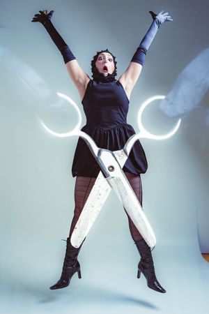 A person in a black dress and white boots performs a jumping pose sequence against a light background.