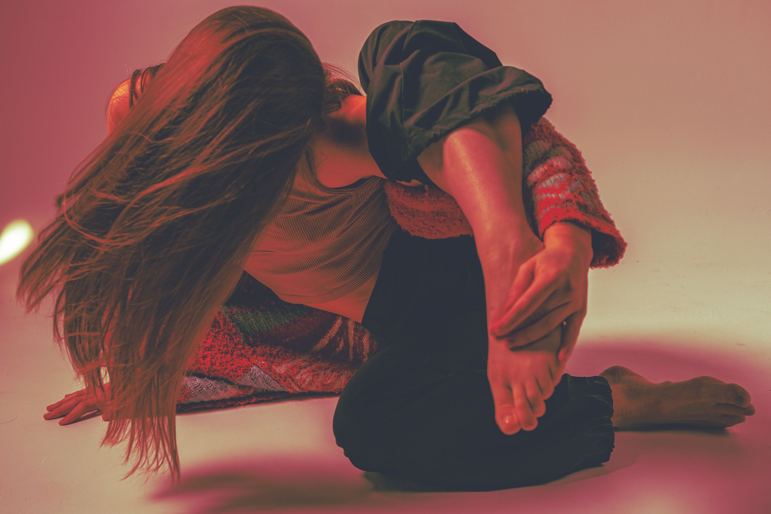 A silhouetted figure lies on the ground in a dramatic red-tinted lighting setup creating an artistic mood.