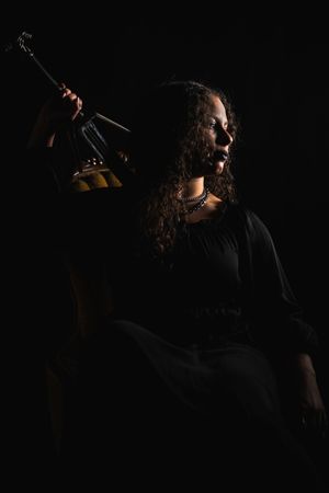Dramatic silhouette of a performer singing passionately on stage with dark lighting and moody atmosphere.