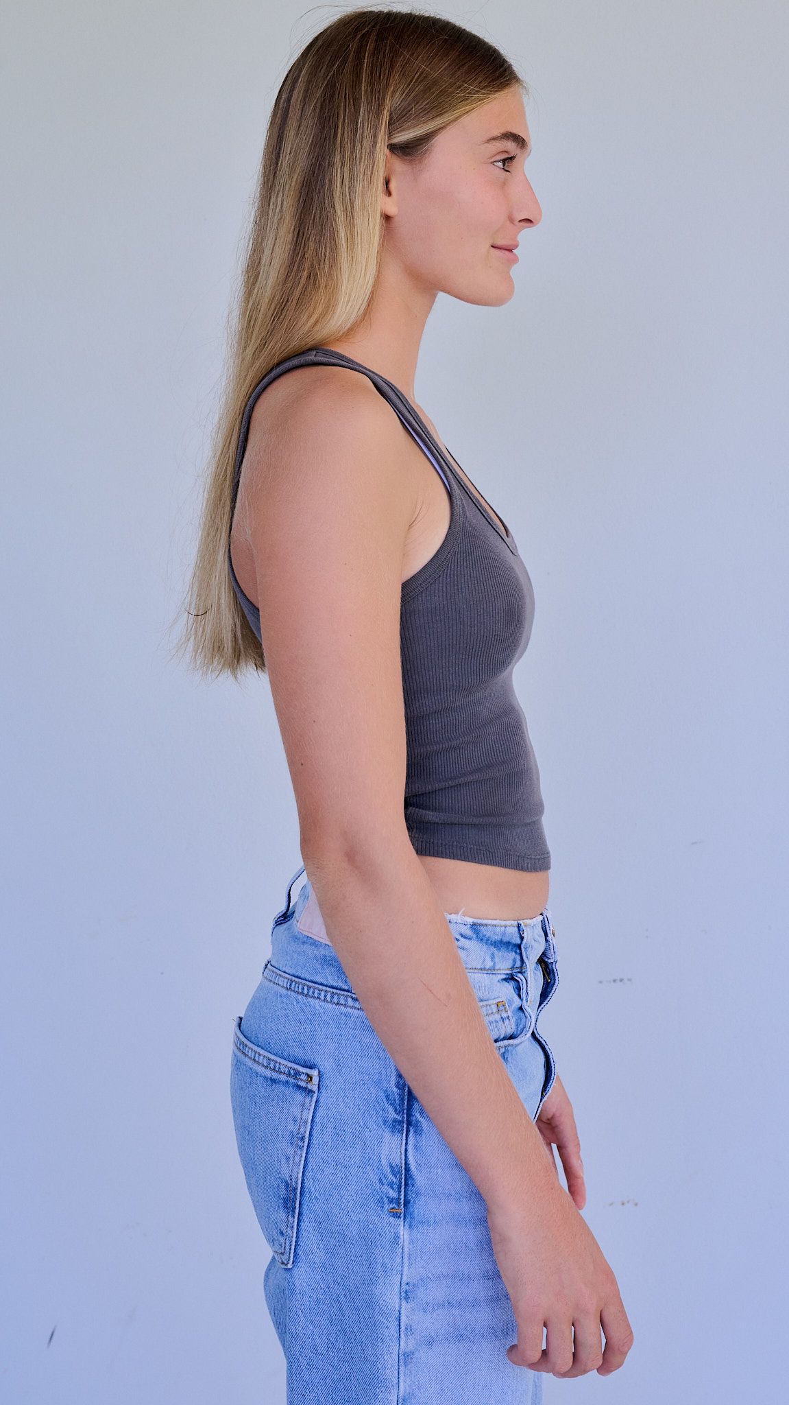 Model poses in white crop top and denim against light blue background in series of artistic fashion shots.