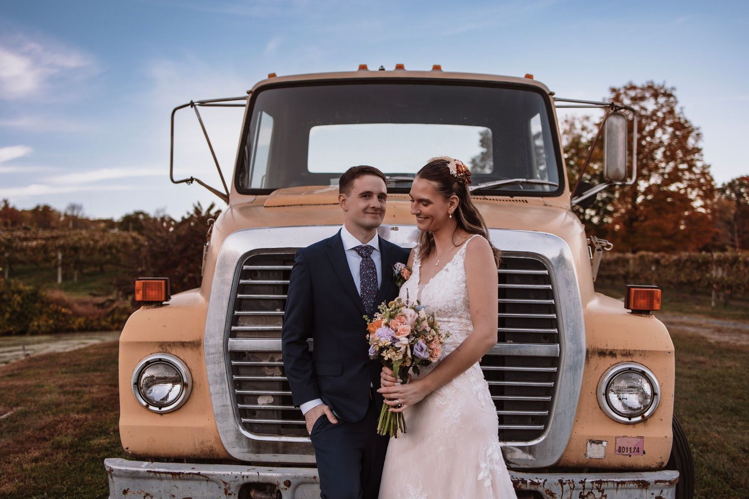 Bride laughing with groom during a candid moment together in front of a rustic truck.