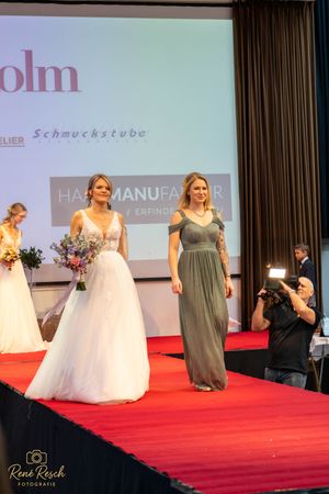 Bridal fashion show featuring wedding gowns and bridesmaid dresses on illuminated runway.