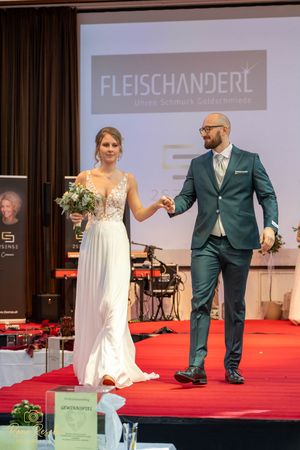 Wedding fashion presentation displaying formal wear and bridal gowns during a runway event.