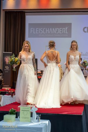 Wedding gowns with lace details and tulle skirts displayed during a bridal fashion show.