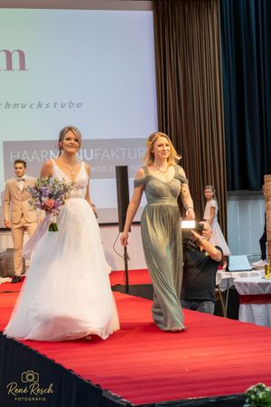 Models present wedding collection with mix of formal gowns and sage green bridesmaid dresses.