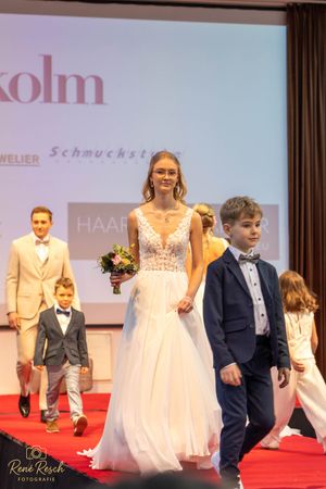Models showcase bridal and formal wear during a wedding fashion show.