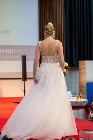 Back view of wedding dress models displaying detailed lace and tulle gowns on fashion runway.