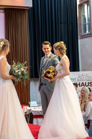 Wedding fashion show models walking runway in white gowns with sunflower bouquets.