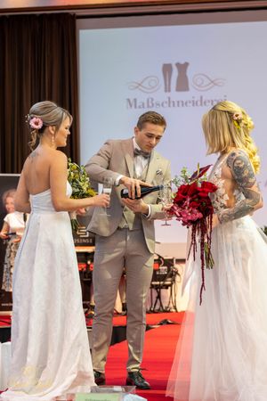 Models showcase elegant wedding attire while walking down illuminated red carpet runway.