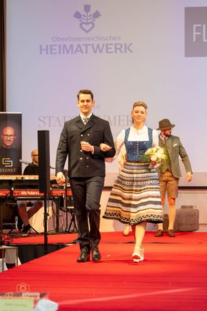 Models showcase traditional Austrian clothing and formal wear during fashion show.