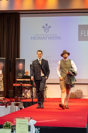 Fashion show on red carpet runway featuring traditional Bavarian and Austrian folk costumes.