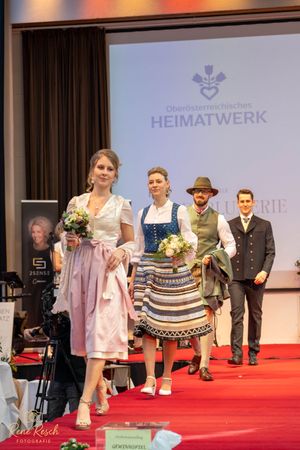 Traditional Alpine fashion show with models displaying authentic regional clothing styles.