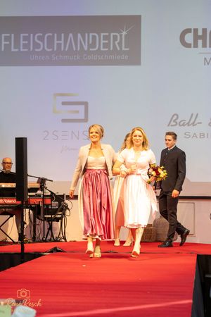 Fashion show featuring traditional dirndl dresses and Alpine wear on red carpet.