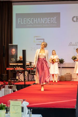 Model walks the runway in a pink and white dirndl dress at the Fleischanderl fashion show.