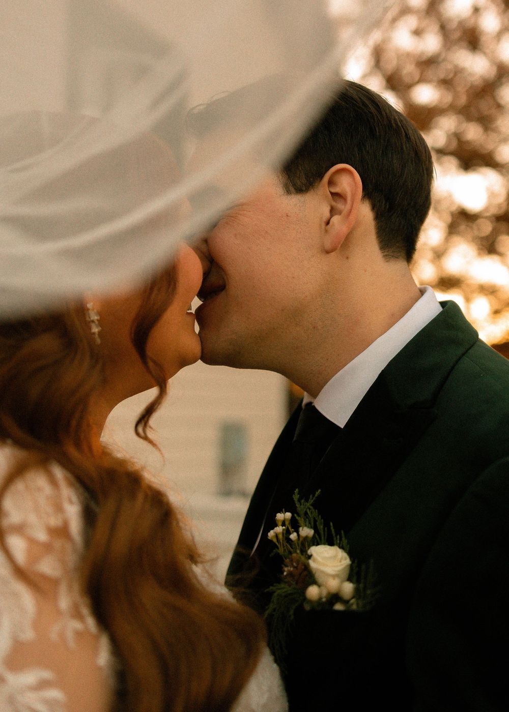 A romantic couple shares an intimate kiss in warm sepia lighting during their wedding ceremony.