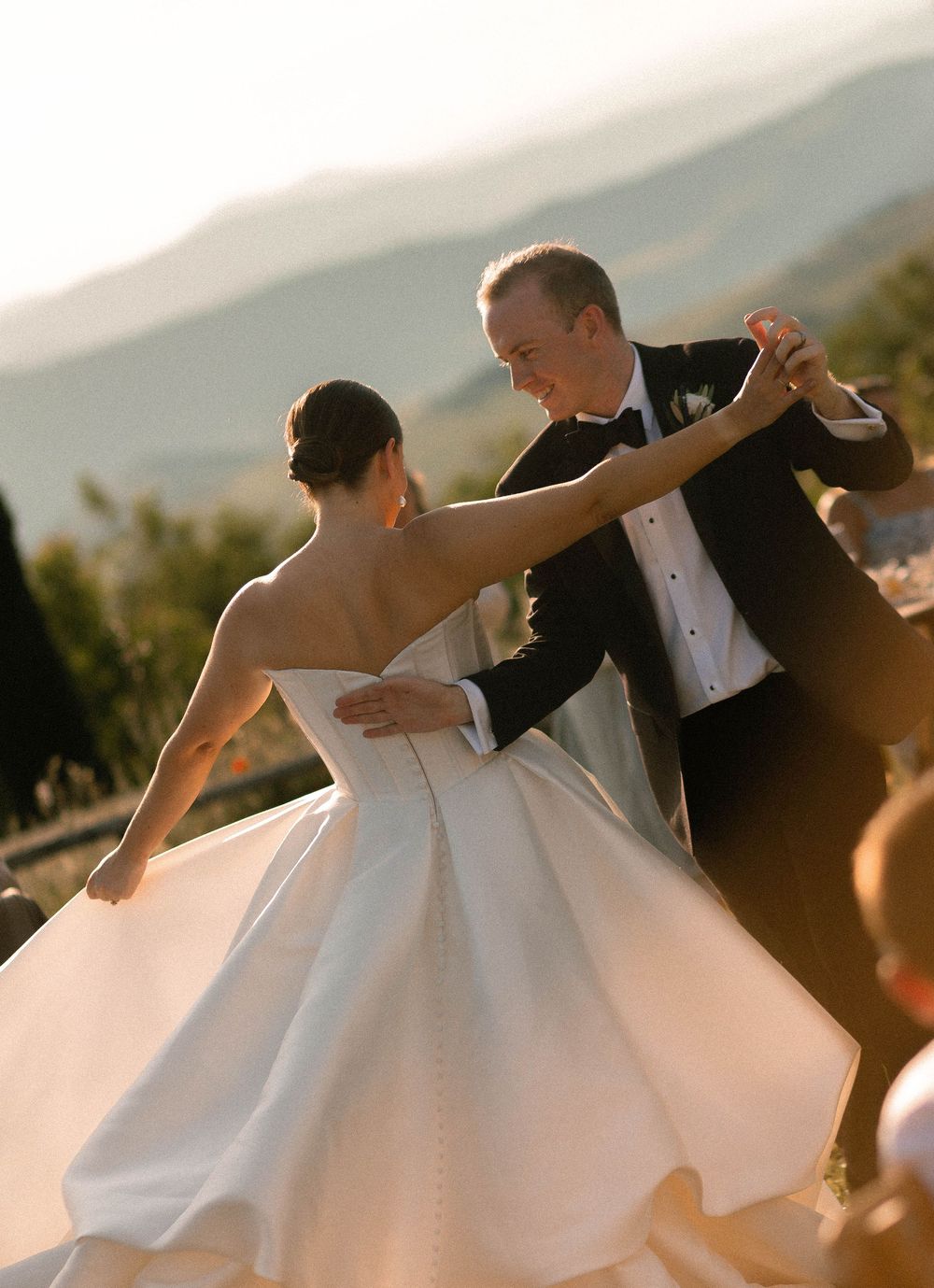 A couple in wedding attire dances together in a series of spinning motion shots at sunset.