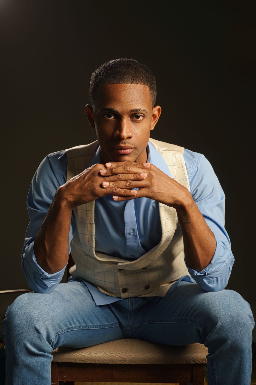 A series of dramatic portraits showing someone in a light blue shirt leaning forward on a chair.