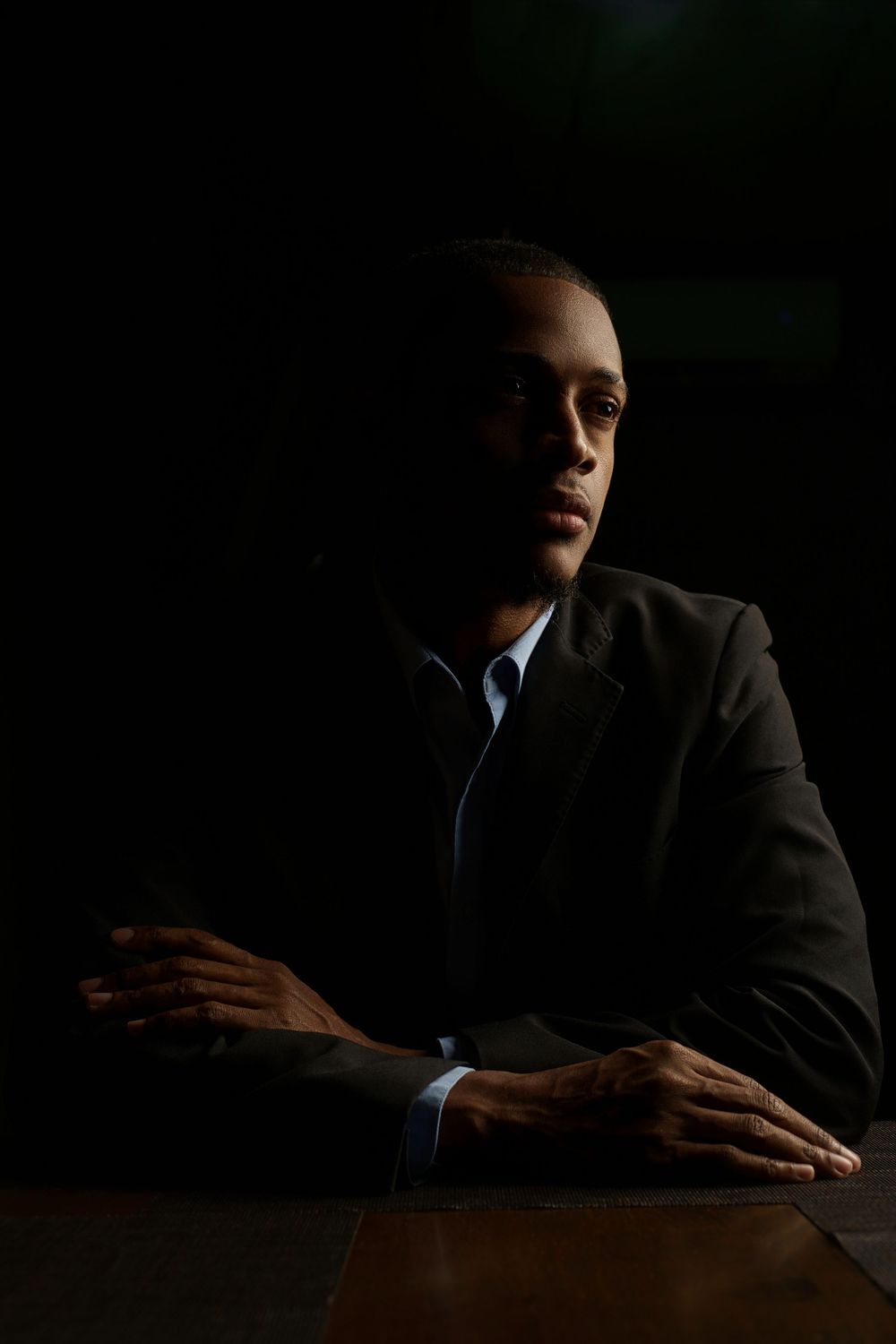A dramatic low-key portrait sequence showing hands resting on a dark surface in moody lighting.