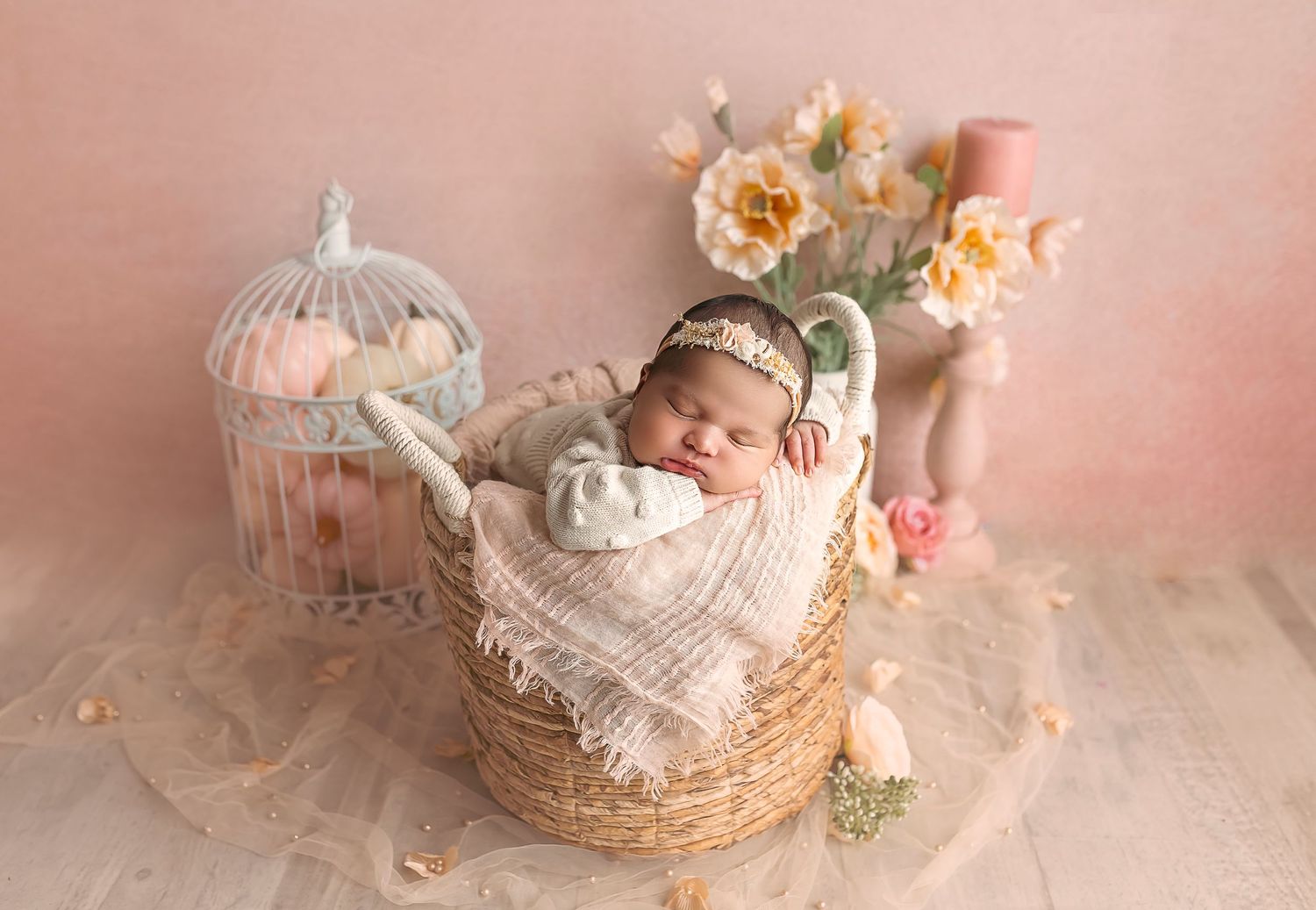 Bebe recien nacida dentro de una canasta alta redonda decorada de color peach y flores