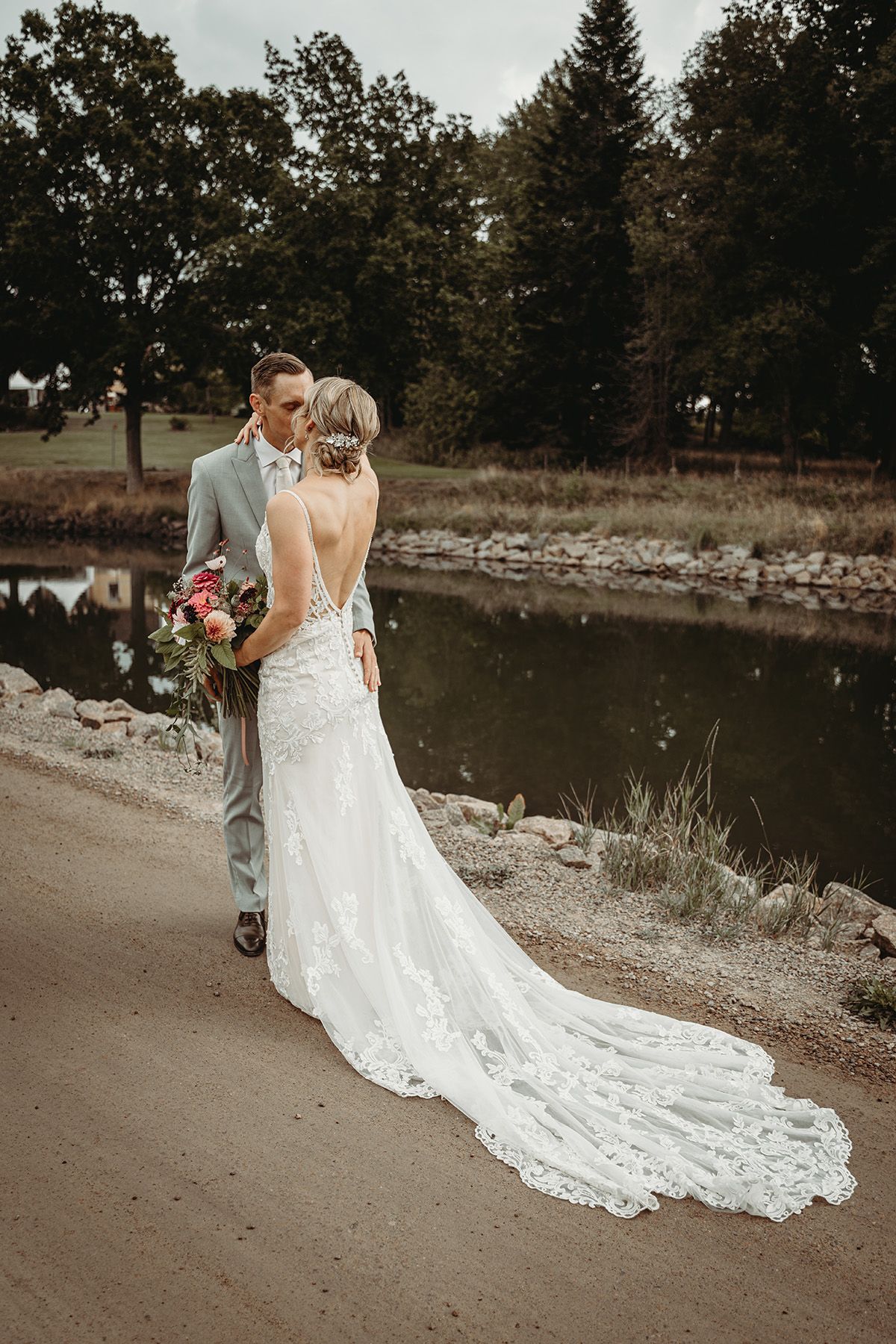 First look fotografering av brudpar vid Göta kanal i Borensberg. Bruden bär en vacker vit brudklänning med öppen rygg och långt släp.