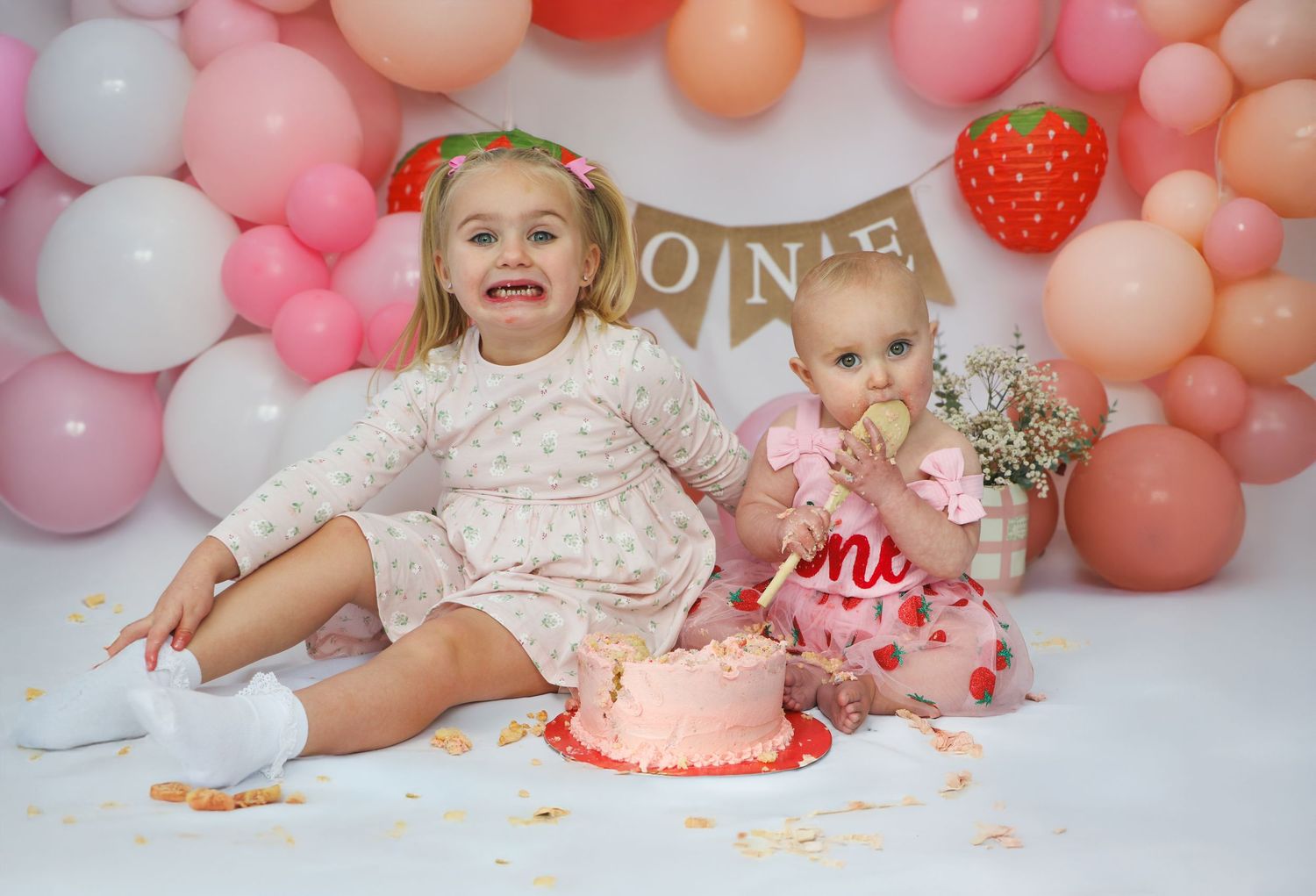 Pink and coral balloon arch installation with peach and white balloons creates a festive party backdrop.