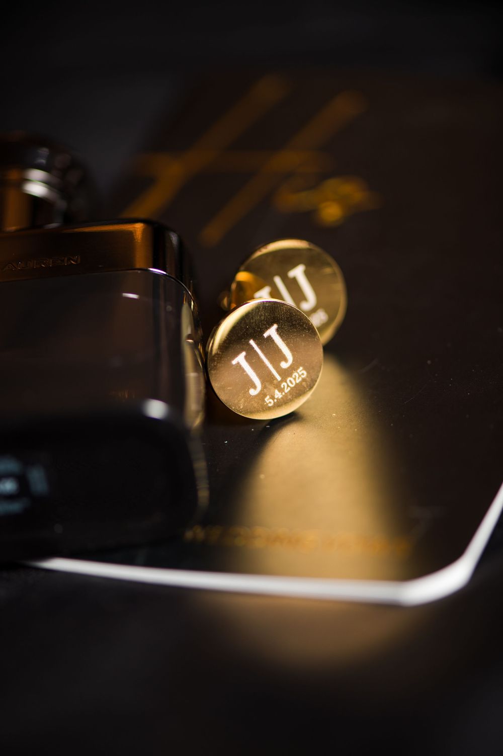 Gold monogrammed cufflinks with initials JT photographed in dramatic lighting.