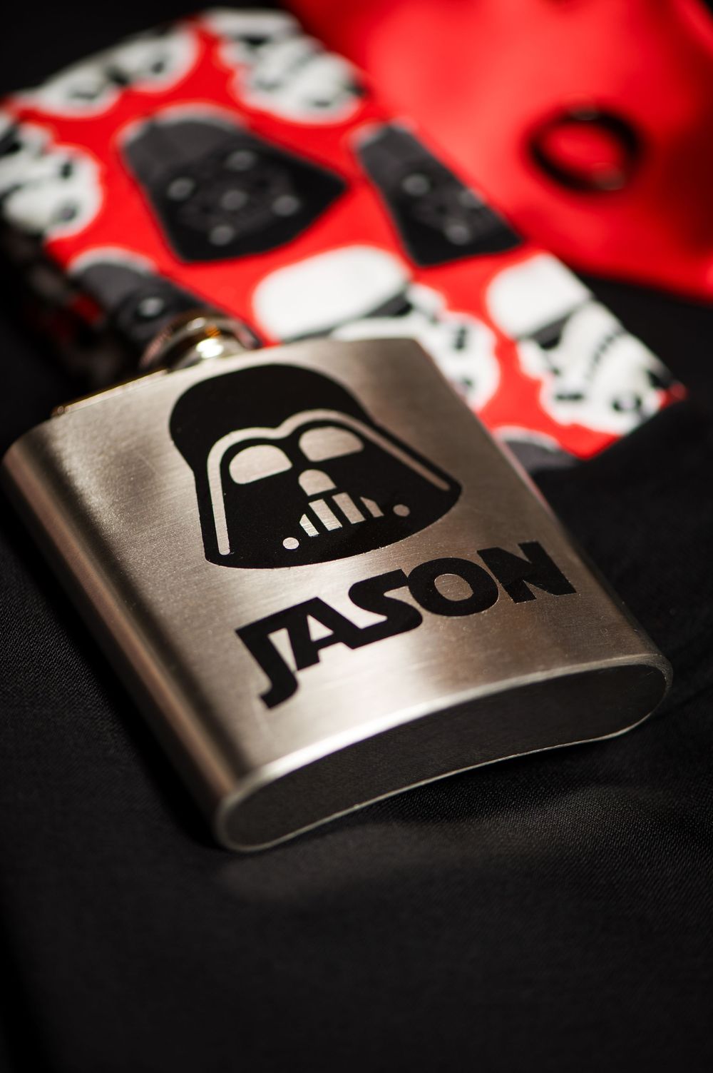 Close-up of Star Wars Darth Vader themed metallic flask against red background.