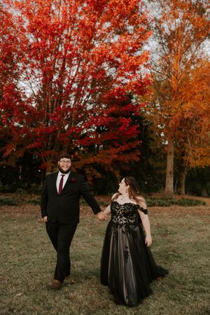 Romantic autumn photoshoot featuring a couple in formal wear against colorful fall trees.