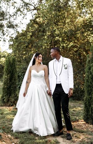 Elegant wedding couple shares intimate moments while walking through a garden setting.