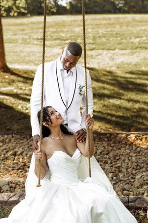 Wedding couple sharing playful moments on a rustic rope swing outdoors.