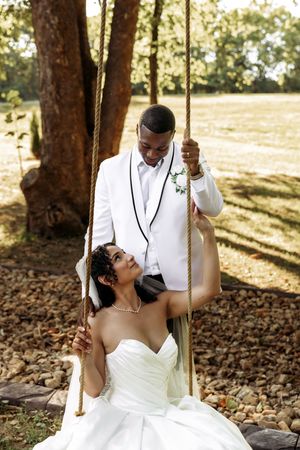 Wedding couple shares intimate moments on a wooden swing during golden hour in a park.