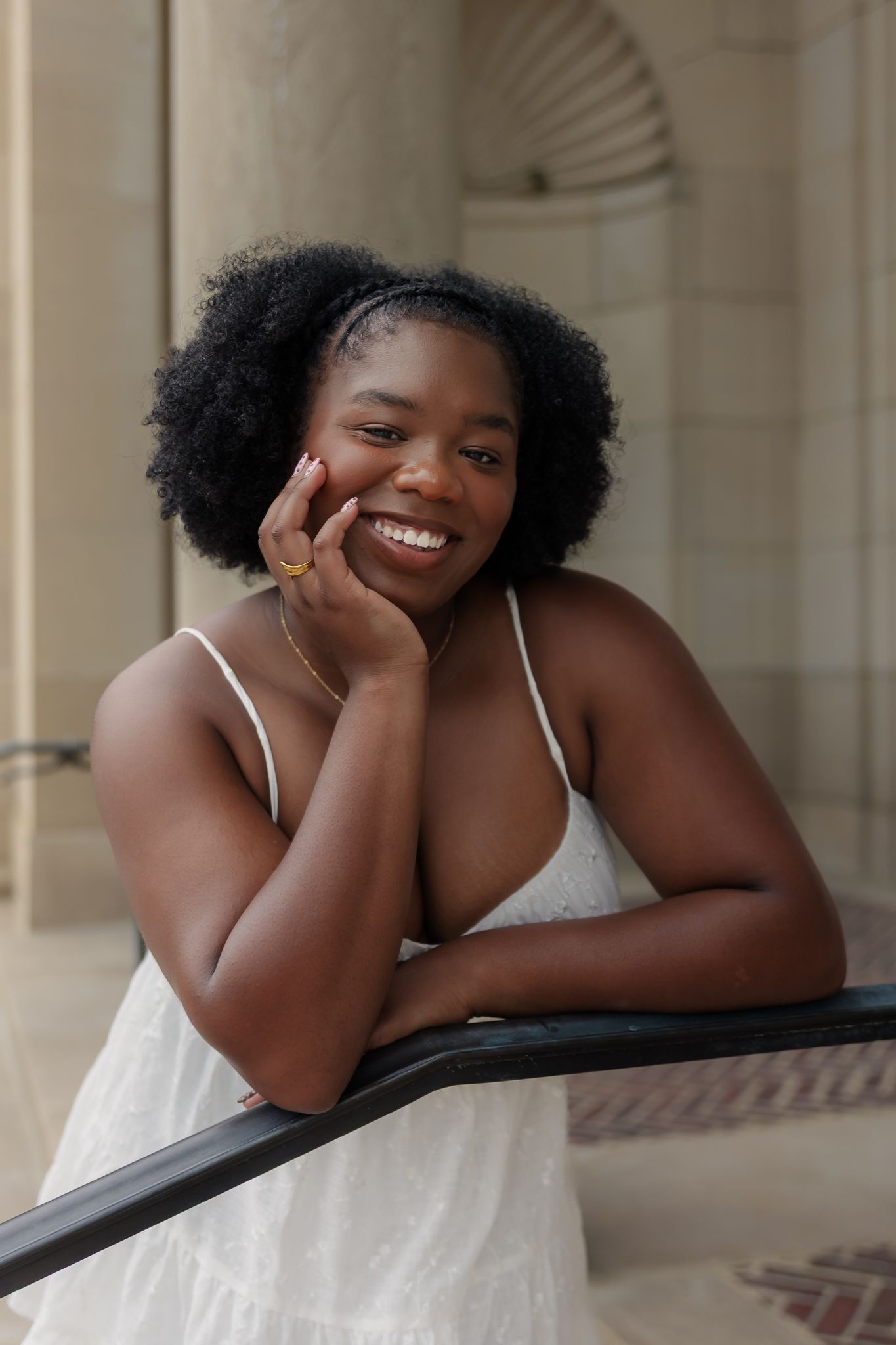 Woman leaning against railiing on stairs for senior photos taken in Ann Arbor on University of Michigan's campus.