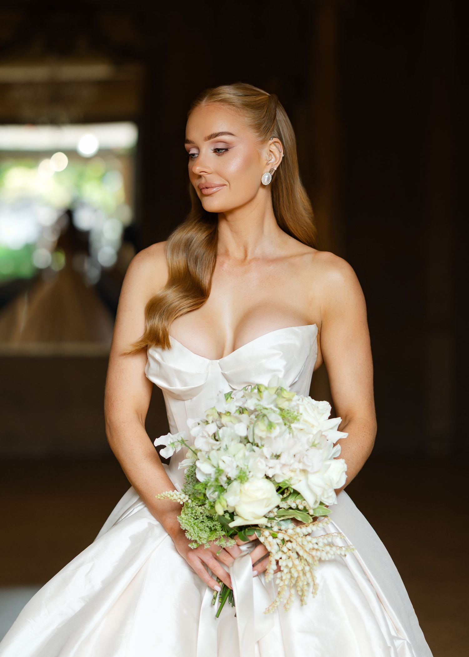 A bride in a white strapless wedding gown holds a delicate bouquet of white and green flowers at Al Ru Farm in Adelaide taken by wading phot