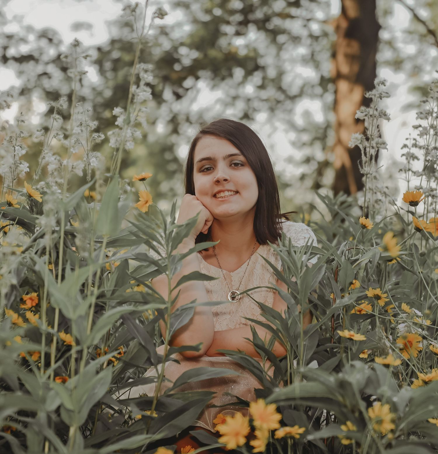 A portrait of someone surrounded by yellow wildflowers in natural lighting.