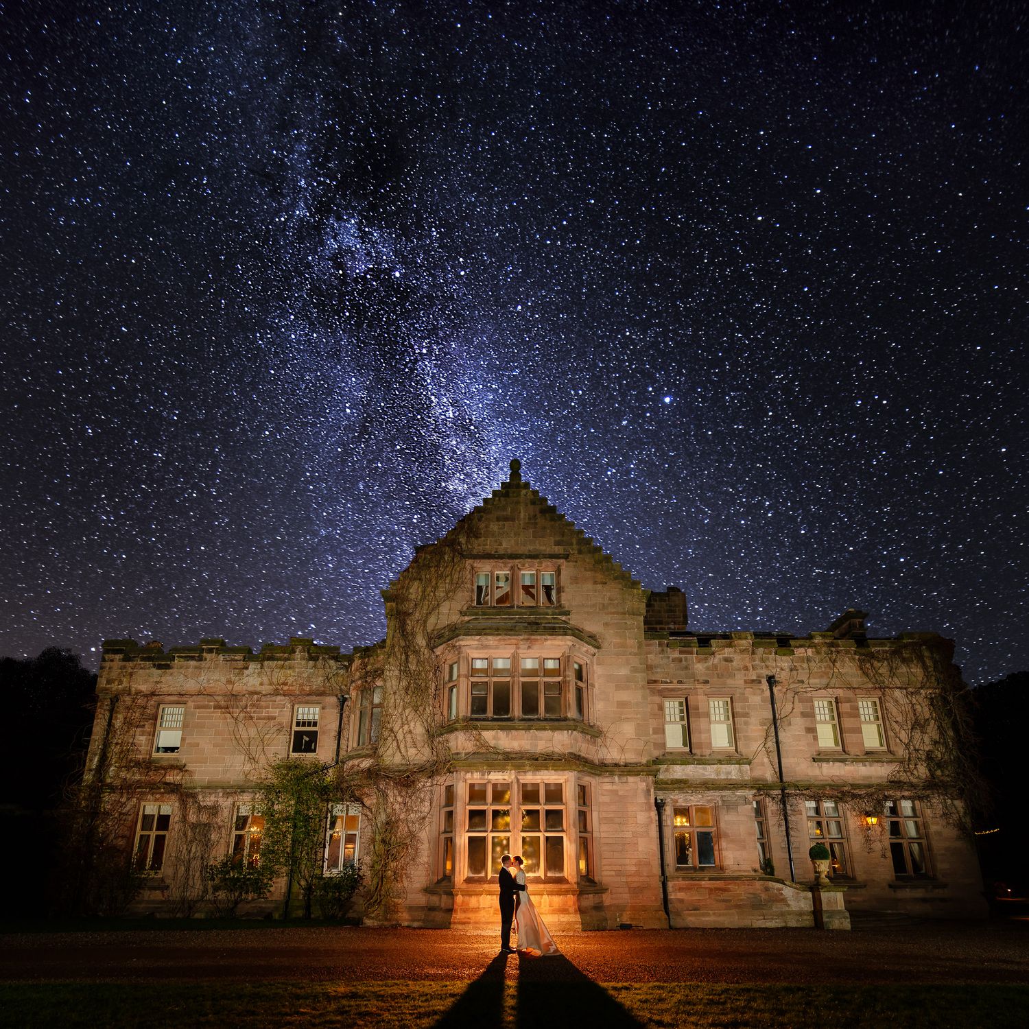 Historic stone building photographed under a starlit night sky with dramatic architectural lighting. Ellingham Hall